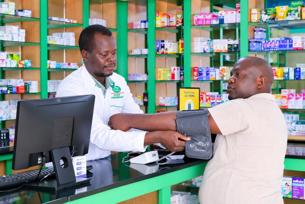 A pharmacist at Given Pharmacy conducting an in-store blood pressure check for a male customer.